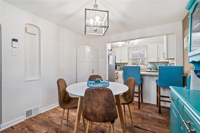 dining room with dark hardwood / wood-style flooring and an inviting chandelier