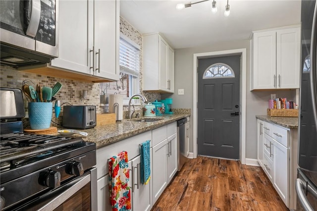 kitchen featuring sink, white cabinets, stainless steel appliances, light stone countertops, and dark wood-type flooring