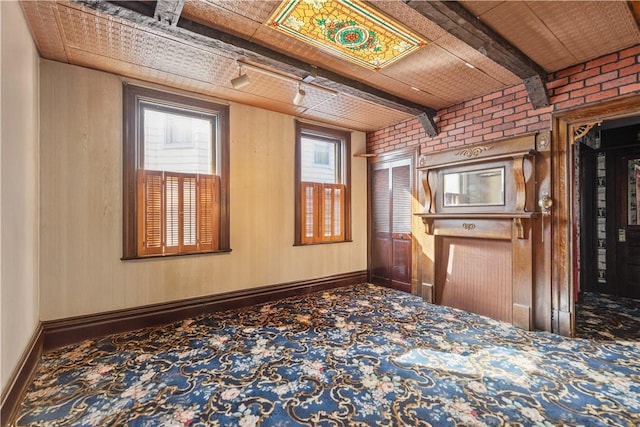 interior space featuring beam ceiling and brick wall