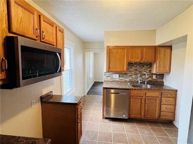 kitchen with sink, light tile patterned floors, appliances with stainless steel finishes, tasteful backsplash, and a textured ceiling