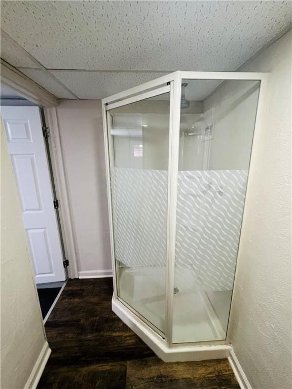 bathroom with a shower with door, hardwood / wood-style floors, and a drop ceiling