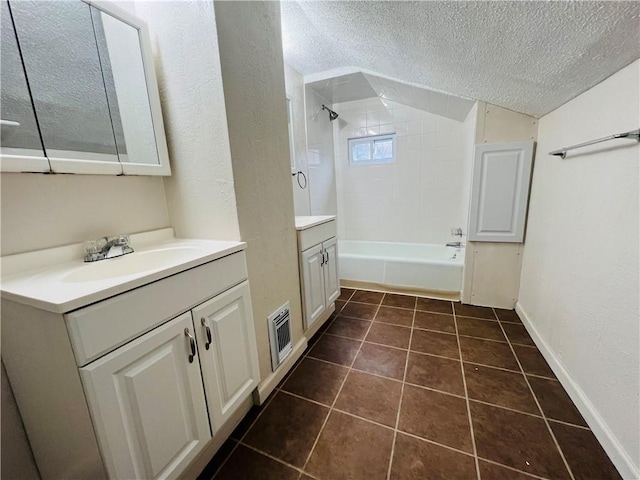 bathroom featuring vaulted ceiling, tile patterned flooring, vanity, tiled shower / bath combo, and a textured ceiling