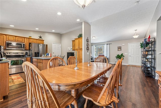 dining space with lofted ceiling, dark hardwood / wood-style floors, and a textured ceiling