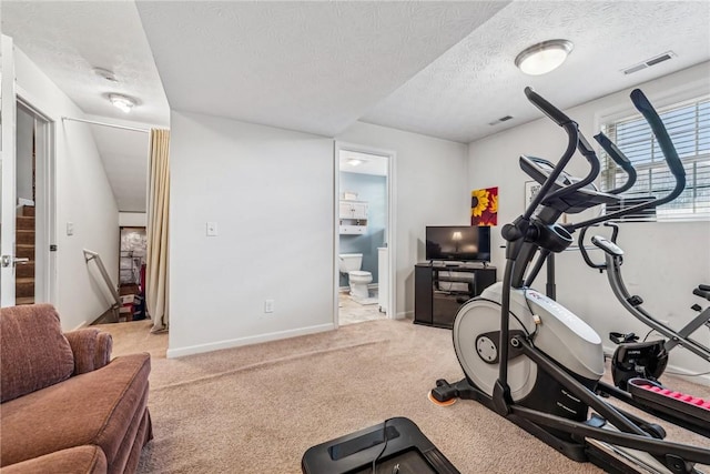 exercise room featuring light colored carpet and a textured ceiling