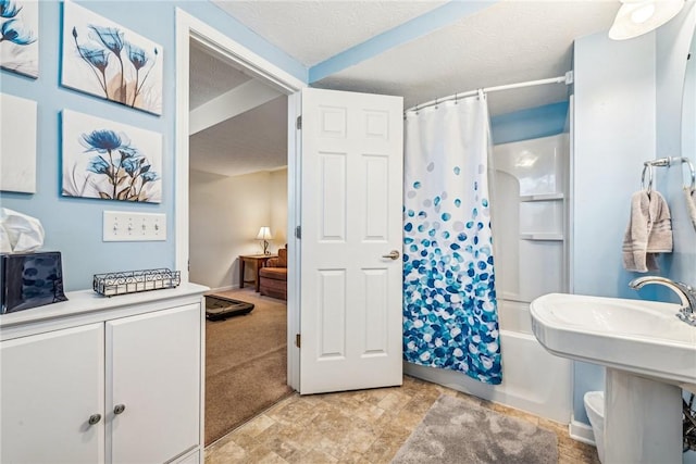 bathroom featuring shower / tub combo with curtain, sink, and a textured ceiling