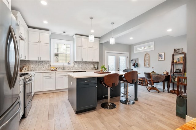 kitchen featuring a kitchen island, decorative light fixtures, white cabinetry, stainless steel appliances, and french doors