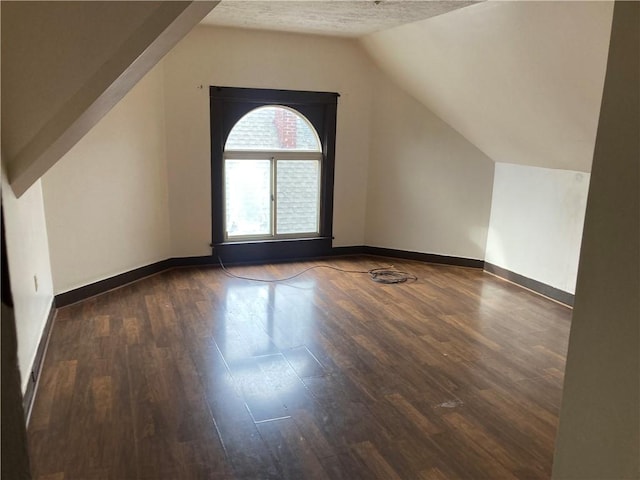 bonus room featuring lofted ceiling, dark hardwood / wood-style floors, and a textured ceiling