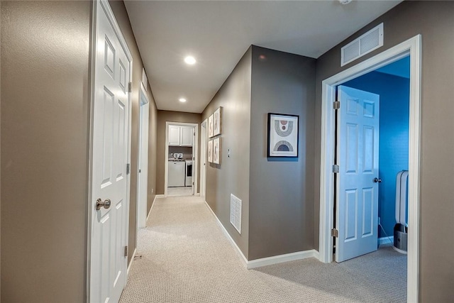 hallway featuring washing machine and clothes dryer and light carpet