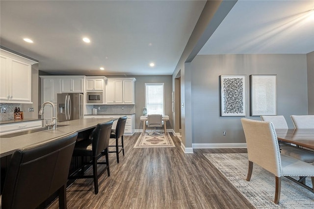 kitchen featuring sink, dark wood-type flooring, white cabinetry, stainless steel appliances, and tasteful backsplash