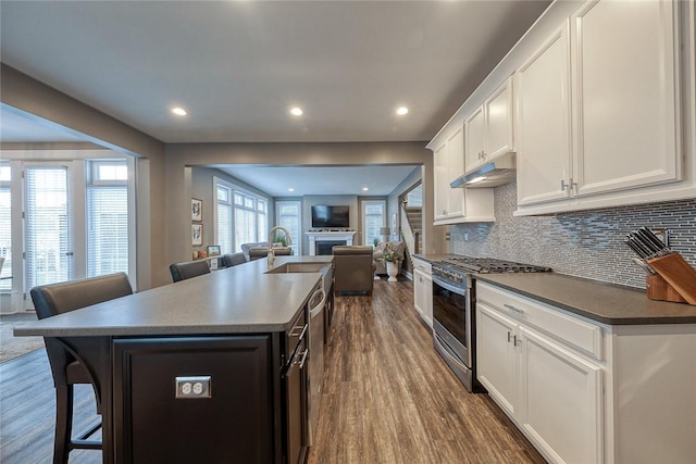 kitchen with a breakfast bar area, a center island, stainless steel range with gas cooktop, dark hardwood / wood-style floors, and white cabinets