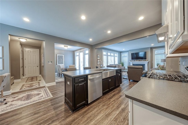 kitchen featuring sink, dark brown cabinets, a center island with sink, dark hardwood / wood-style flooring, and stainless steel dishwasher