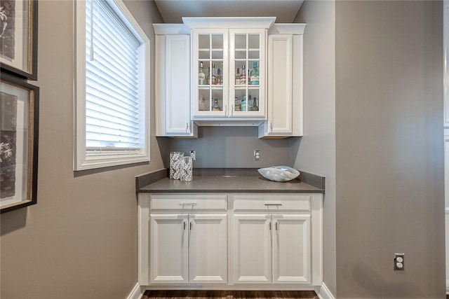 bar featuring white cabinetry and dark stone countertops