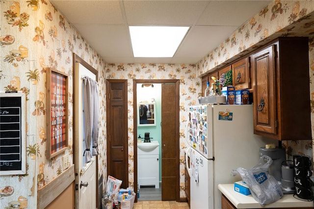 kitchen with white fridge, sink, and a paneled ceiling