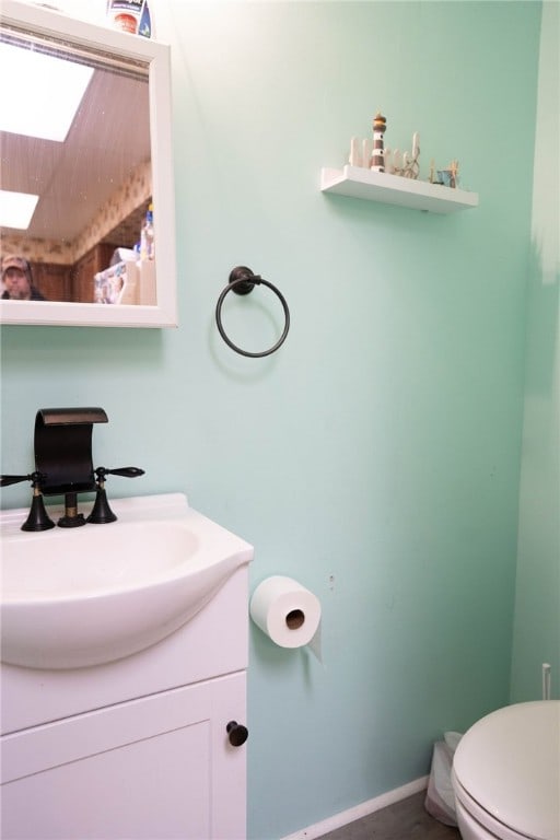 bathroom with vanity, toilet, and a skylight