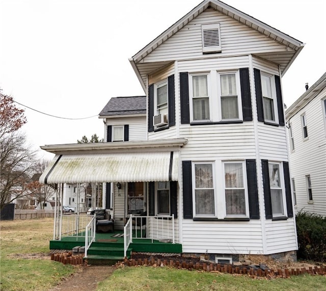 view of front of property with a front yard, covered porch, and cooling unit