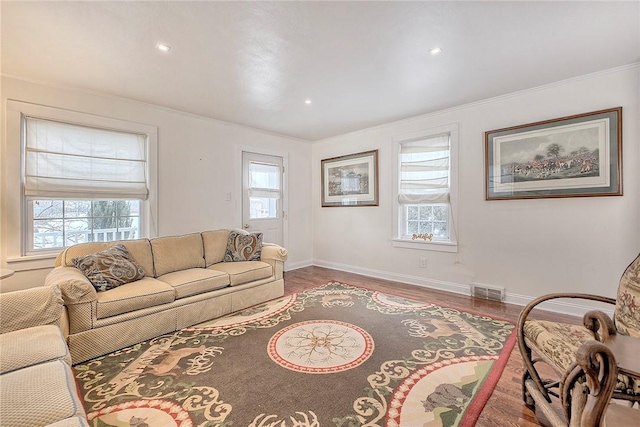 living room featuring hardwood / wood-style flooring, ornamental molding, and plenty of natural light