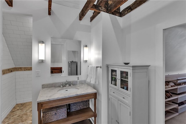 bathroom with beamed ceiling and vanity