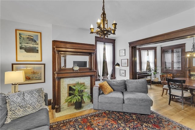 living room with an inviting chandelier, a wealth of natural light, and light wood-type flooring