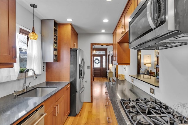 kitchen featuring sink, decorative light fixtures, light hardwood / wood-style flooring, and appliances with stainless steel finishes