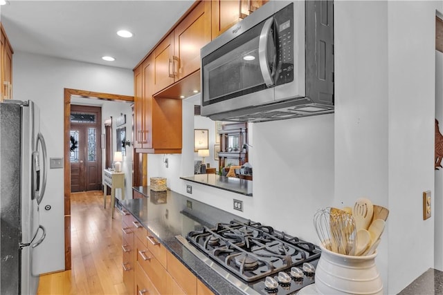 kitchen with dark stone countertops, light hardwood / wood-style floors, and appliances with stainless steel finishes