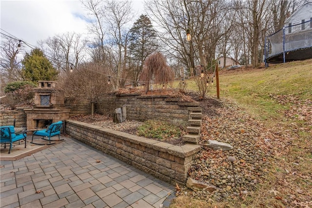 view of patio with an outdoor fireplace and a trampoline