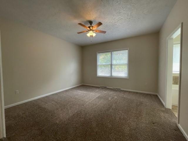 carpeted empty room featuring ceiling fan and a textured ceiling