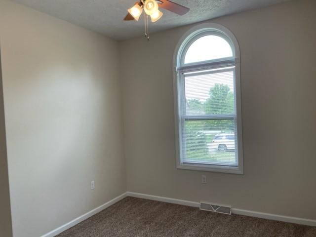 carpeted empty room with ceiling fan and a textured ceiling