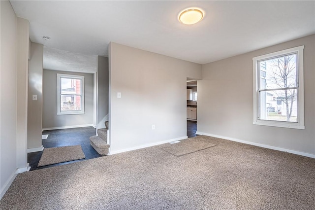 unfurnished room featuring dark colored carpet and plenty of natural light