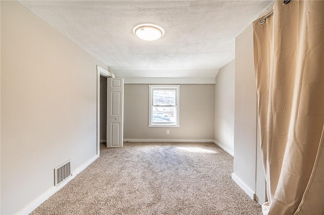 unfurnished room with a textured ceiling and carpet flooring