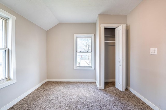 unfurnished bedroom featuring vaulted ceiling, carpet floors, and a closet