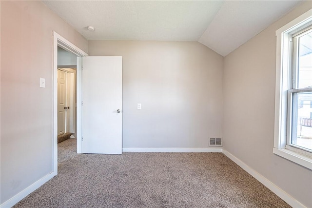 unfurnished room featuring lofted ceiling and carpet floors