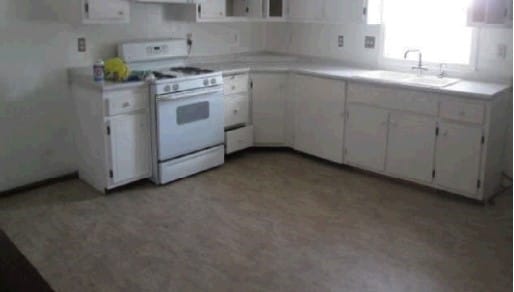 kitchen with white cabinetry, white gas range, and sink