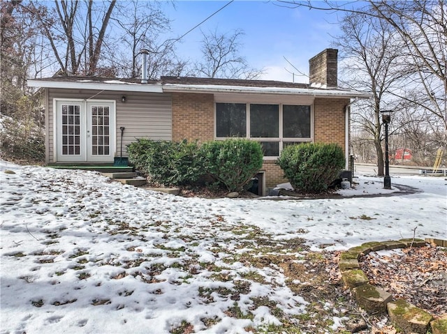 snow covered house featuring french doors