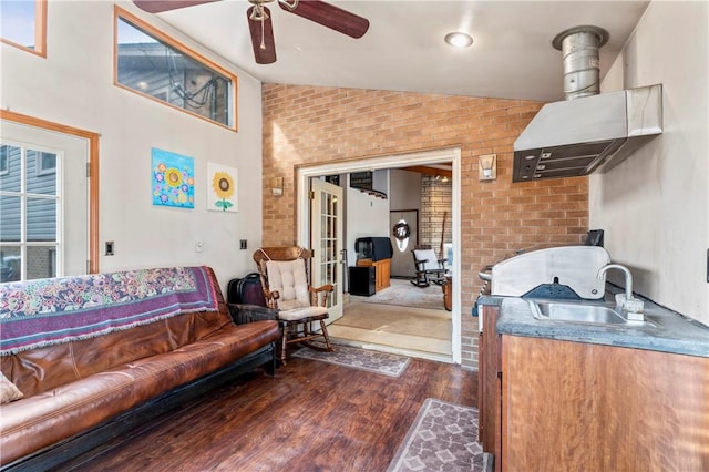 living room with lofted ceiling, sink, ceiling fan, brick wall, and dark hardwood / wood-style flooring