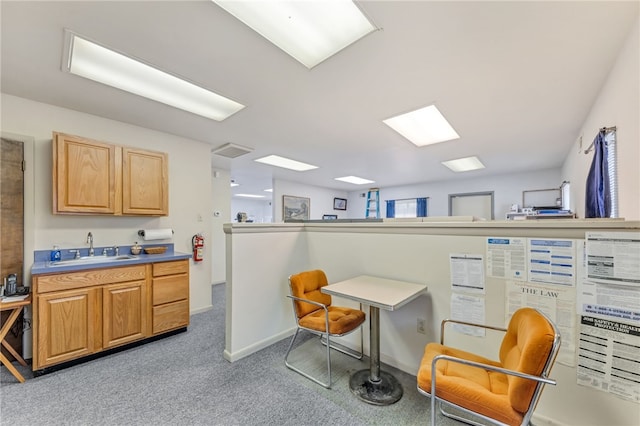 interior space with a breakfast bar area, sink, light carpet, and light brown cabinetry