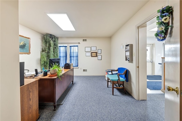 office space with a skylight and dark colored carpet