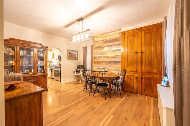 dining room with wooden walls and light hardwood / wood-style floors