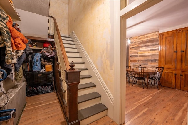 stairway with wooden walls and hardwood / wood-style floors