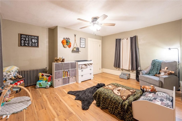 bedroom with hardwood / wood-style flooring, radiator, and ceiling fan