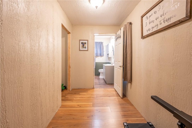 corridor with light hardwood / wood-style floors and a textured ceiling