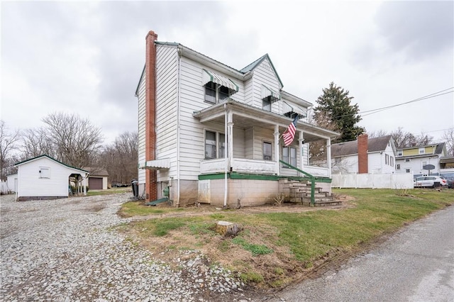 view of front of house featuring a garage, an outdoor structure, a front lawn, and a porch