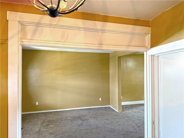 carpeted spare room with an inviting chandelier