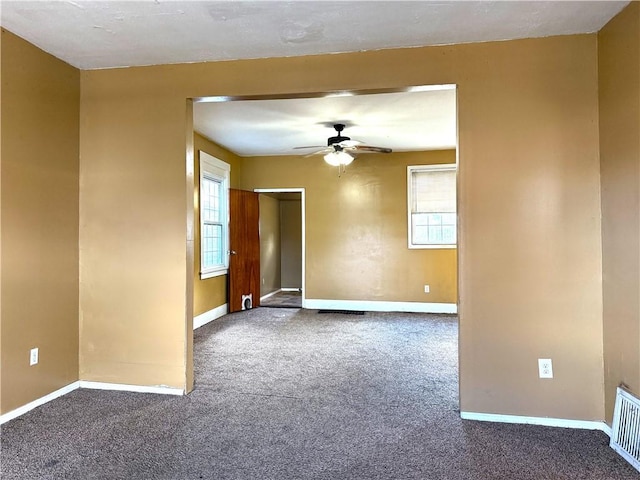 empty room featuring a wealth of natural light, ceiling fan, and carpet flooring