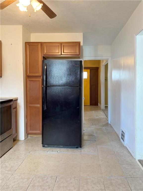 kitchen featuring black fridge, ceiling fan, and stove