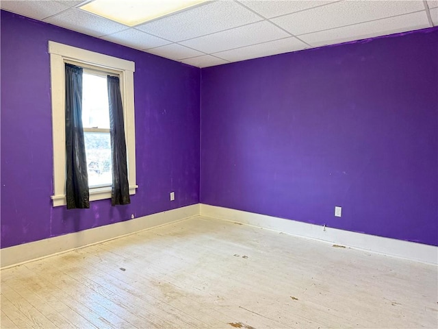 spare room featuring hardwood / wood-style floors and a drop ceiling