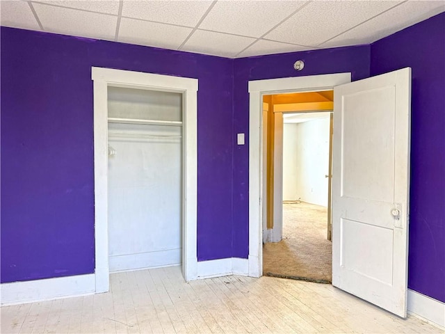 unfurnished bedroom featuring a drop ceiling and a closet