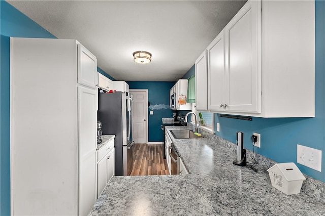 kitchen featuring light stone counters, hardwood / wood-style flooring, stainless steel appliances, and white cabinets