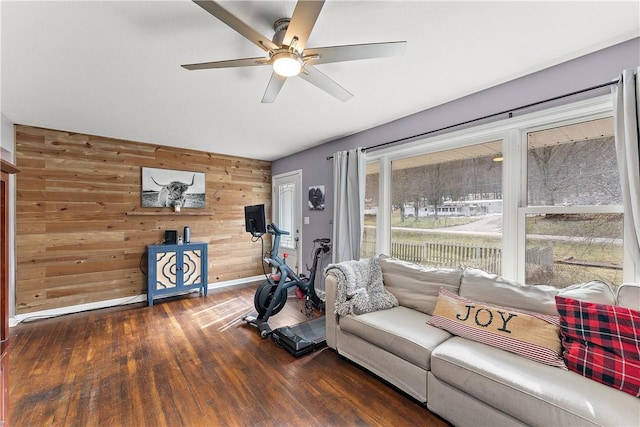 living room with ceiling fan, dark hardwood / wood-style floors, and wood walls