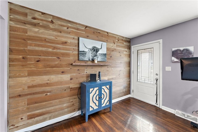 foyer entrance featuring dark hardwood / wood-style floors and wooden walls