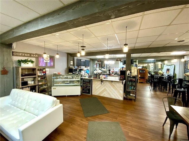 interior space with wine cooler, dark wood-type flooring, hanging light fixtures, kitchen peninsula, and a drop ceiling